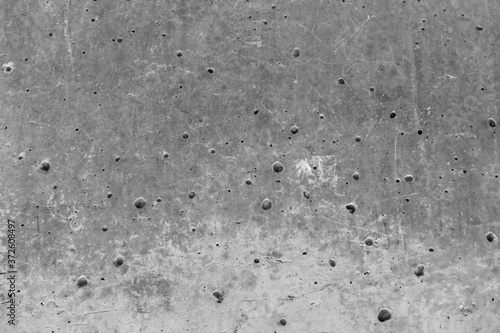 Texture of an aged and weathered grey concrete exterior wall. Plenty of holes around the surface. Conctruction and materials