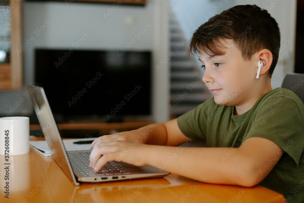 Focused kid using laptop at home Focused kid using laptop at home