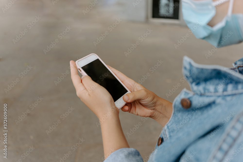 © Jake Jakab/ADDICTIVE STOCK - Side view of crop anonymous female in disposable mask and denim jacket browsing mobile phone while standing on city street © Jake Jakab/ADDICTIVE STOCK - Side view of crop anonymous female in disposable mask and denim jacket browsing mobile phone while standing on city street