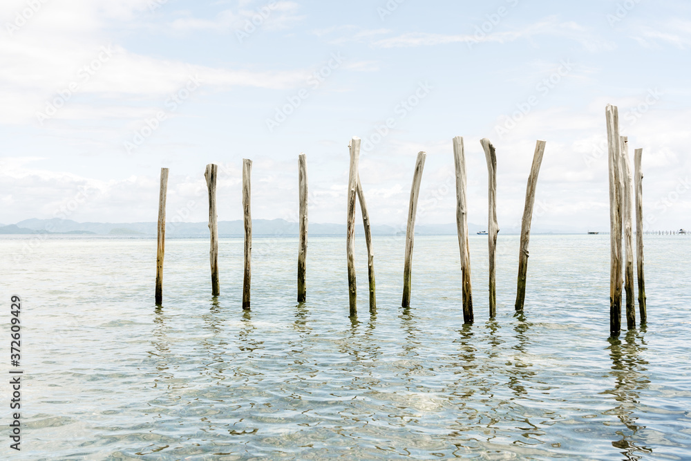 Shabby wooden poles placed in clear water of sea on sunny day on background of blue sky Shabby wooden poles placed in clear water of sea on sunny day on background of blue sky