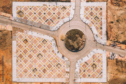 From above aerial view of road intersection with traffic roundabout in dry terrain with ornamental infrastructure