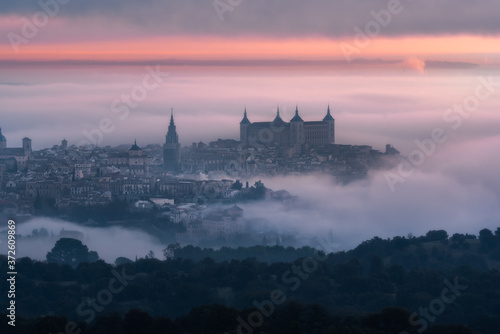 From above wonderful landscape of medieval castle built over city in misty colorful sunrise
