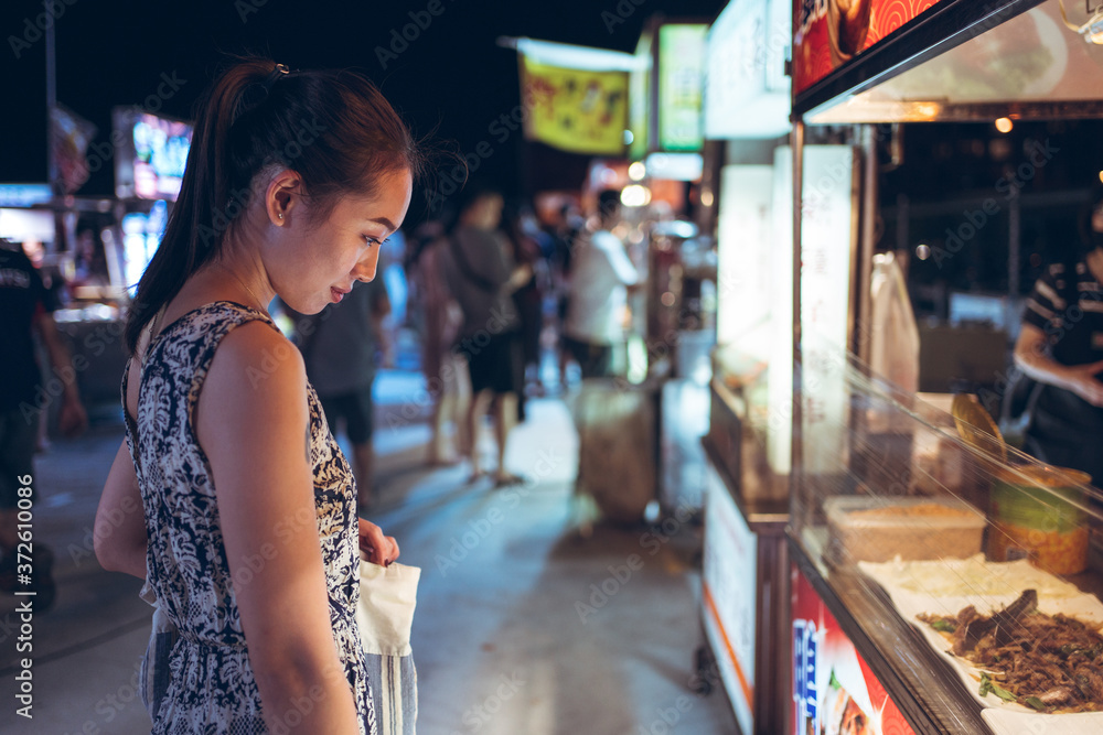 Side view of female in summer dress standing near counter on crowded ...