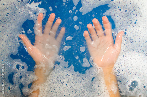 the hands of a child in the blue water of the pool