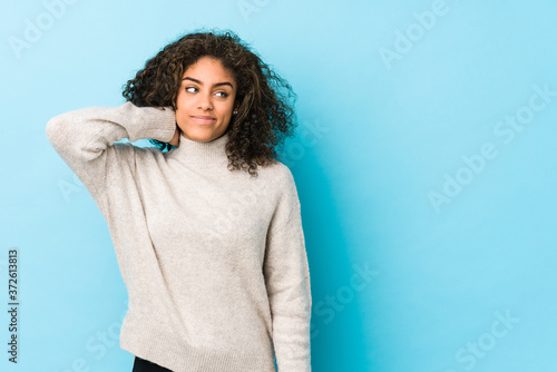 Fényképezés Young african american curly hair woman touching back of head, thinking and making a choice