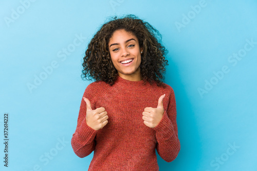 Young african american curly hair woman raising both thumbs up, smiling and confident. photo