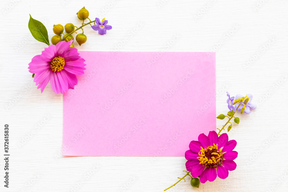 notepaper with pink flowers cosmos ,purple flowers arrnagement flat lay postcard style on background white wooden