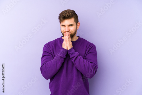 Young caucasian man isolated on purple background making up plan in mind, setting up an idea.