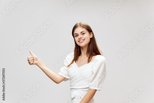 Woman showing thumb up smile white dress studio 