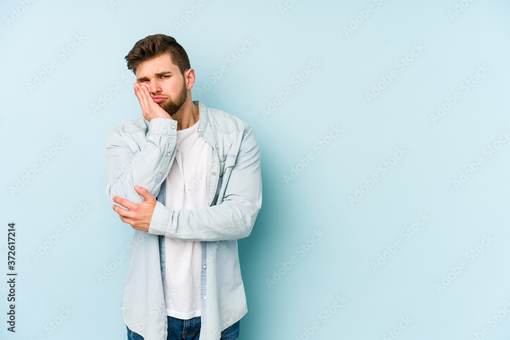 Young caucasian man isolated on blue background who is bored, fatigued and need a relax day. Young caucasian man isolated on blue background who is bored, fatigued and need a relax day.