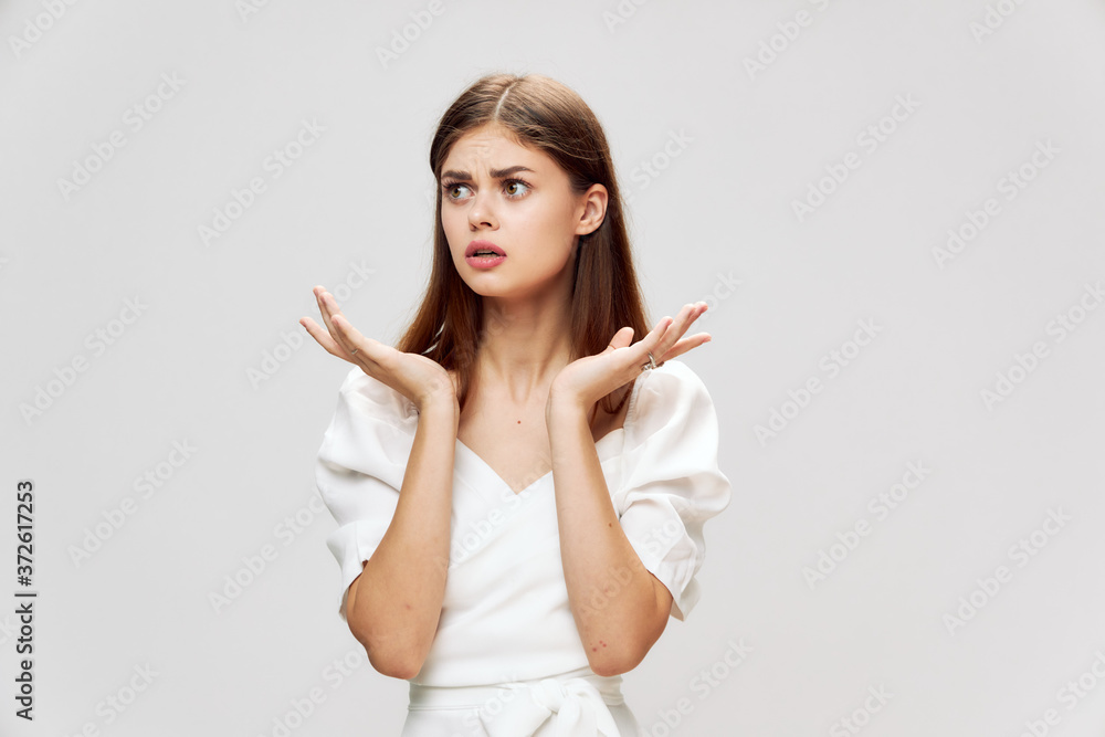 Woman looking to the side displeased facial expression hands in front of her gray background Woman looking to the side displeased facial expression hands in front of her gray background