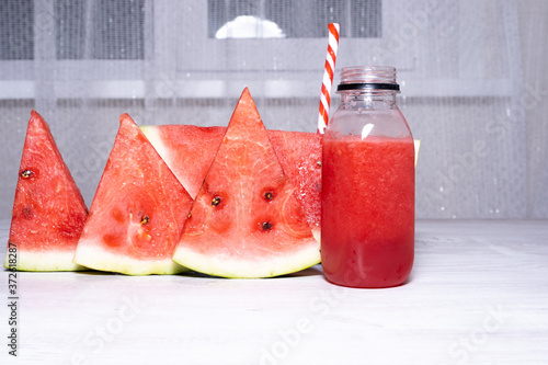 Watermelon smoothie and slices of fresh red watermelon on white wooden table background. copy space