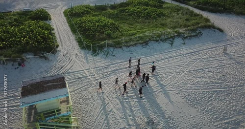 drone shot of people walking on the beach by a lifehouse stand photo