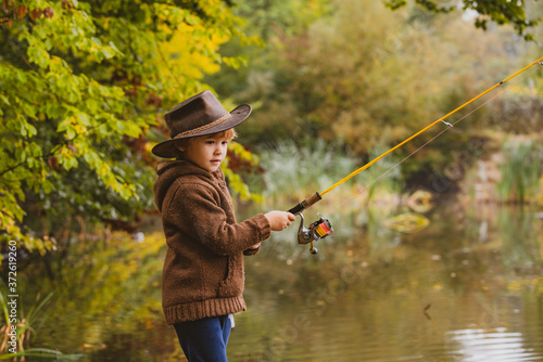 Kid with fishing rod. Child learning how to fish, holding a rod on a lake.