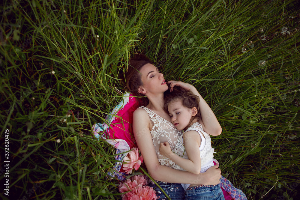 Naklejka premium mother and daughter lie on a green field