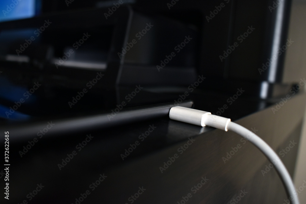 Charger with tablet on the table. Selective focus on the USB cable that plugging to the tablet. Charger with tablet on the table. Selective focus on the USB cable that plugging to the tablet.