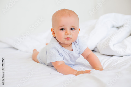 Cute baby boy smiling lies in the bed of the house. bedding for children