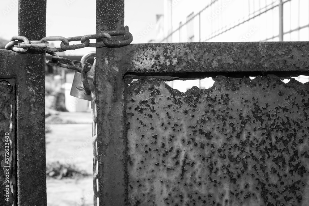 evocative image of rusty gate part with chain and lock in black and white evocative image of rusty gate part with chain and lock in black and white