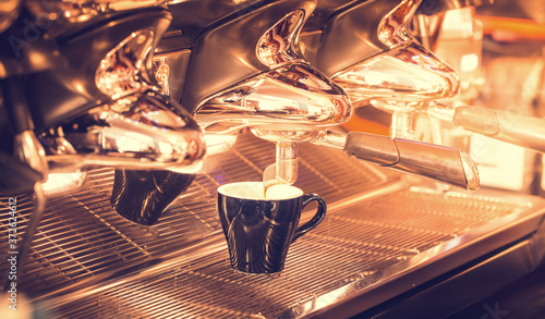 Morning coffee prepared in a cafe. Coffee from a professional coffee machine. Preparing an aromatic cup of coffee. Shallow depth of field.