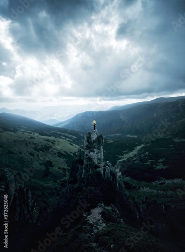 a man stands on a rock against the background of a mountain landscape in cloudy weather