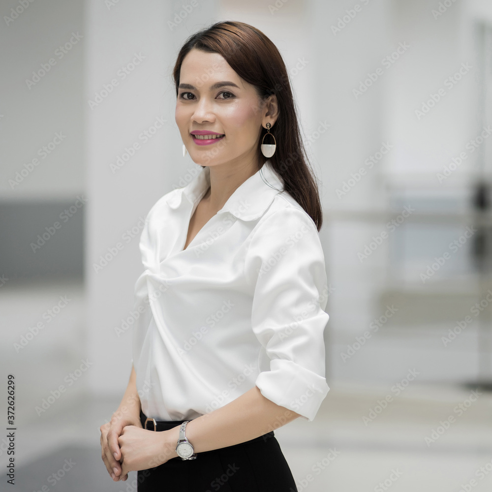 Portrait of a cheerful middle-age businesswoman in business suit standing in the company building with confidence arms crossed. Modern businesswoman in the office with copy space. stock photo. Portrait of a cheerful middle-age businesswoman in business suit standing in the company building with confidence arms crossed. Modern businesswoman in the office with copy space. stock photo.