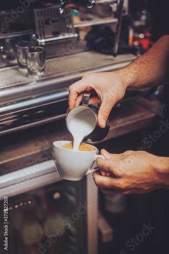 Man making an cappuccino by pouring fresh foam milk