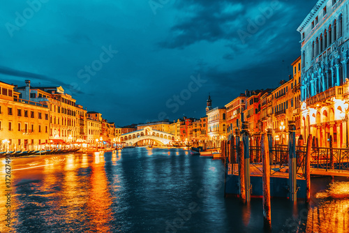 Rialto Bridge (Ponte di Rialto) or Bridge of Sighs and view of the most beautiful canal of Venice - Grand Canal and boats, gondolas, mansions along. Night view. Italy. © BRIAN_KINNEY