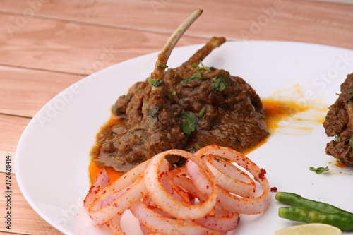 Mutton curry Served with onion over wooden background. photo