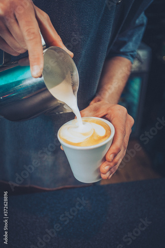 barista poring milk in cafe late