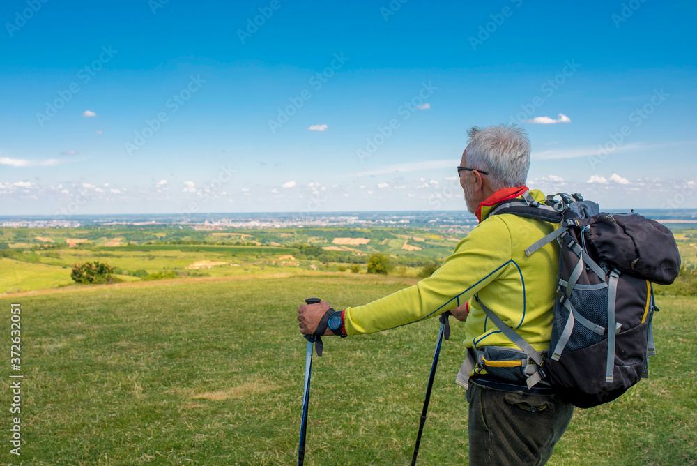 Active Caucasian senior man hiking in high mountains with beautiful nature landscape in the background