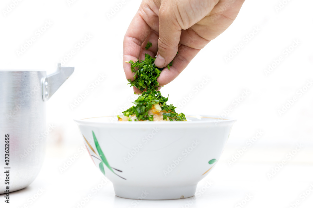 Hands throw greens on soup