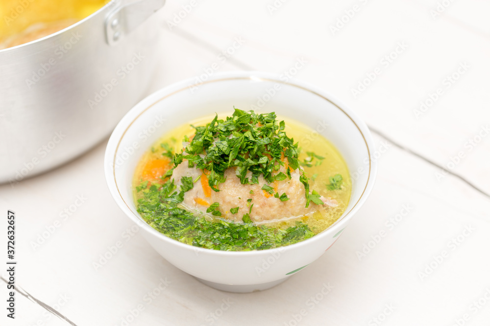 chicken soup on a white table, sprinkled with herbs on top
