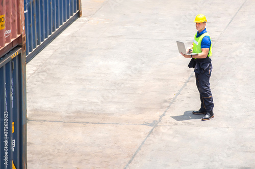 Industrial worker working at cargo freight logistic warehouse wit computer tablet for online assignment. Import and export business.