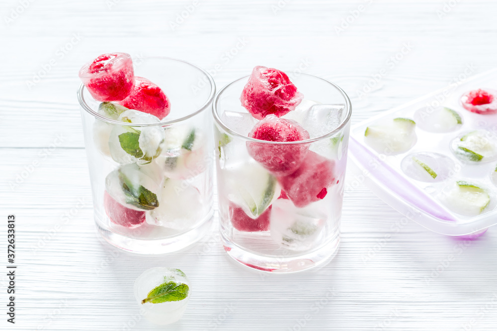 Cocktail glasses with berries in ice cubes on white table Cocktail glasses with berries in ice cubes on white table