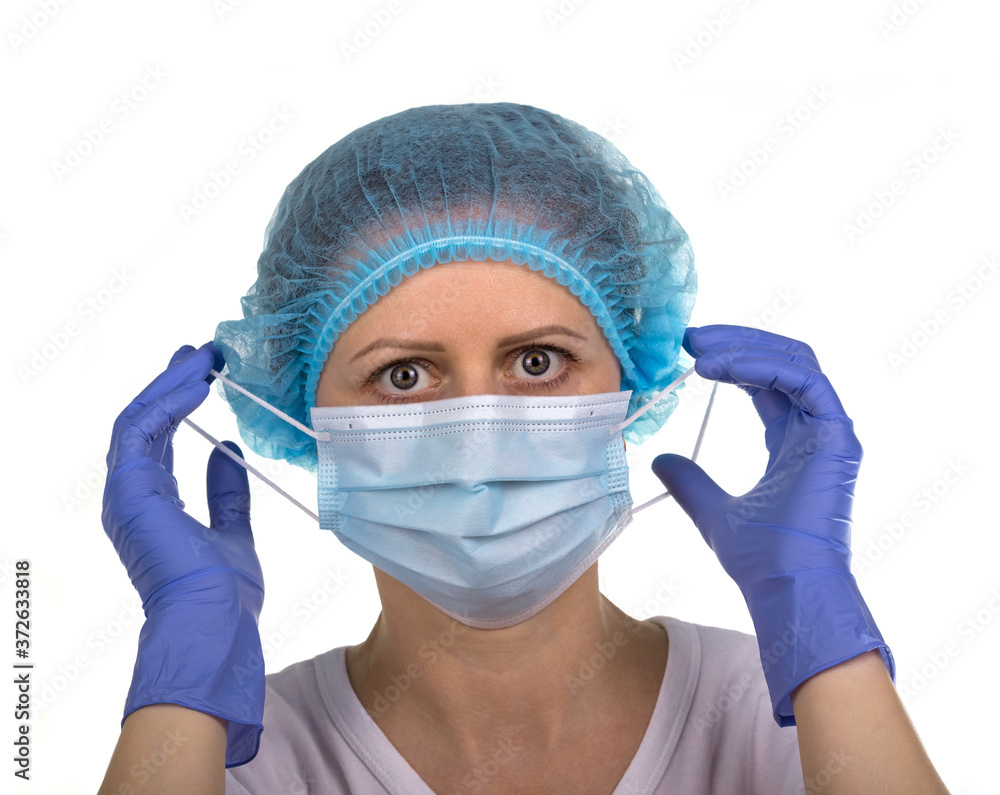 Woman wearing a medical cap and gloves puts on a protective mask Woman wearing a medical cap and gloves puts on a protective mask