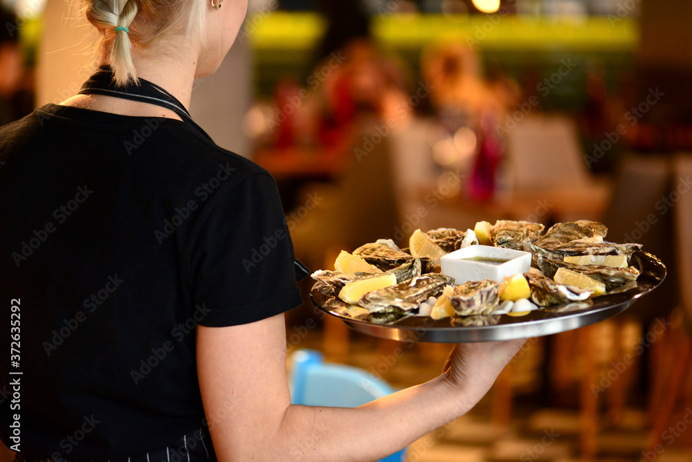 Close-up of steamed clams. Waiter holds a plate with clams in a restaurant. Sea food cuisine.