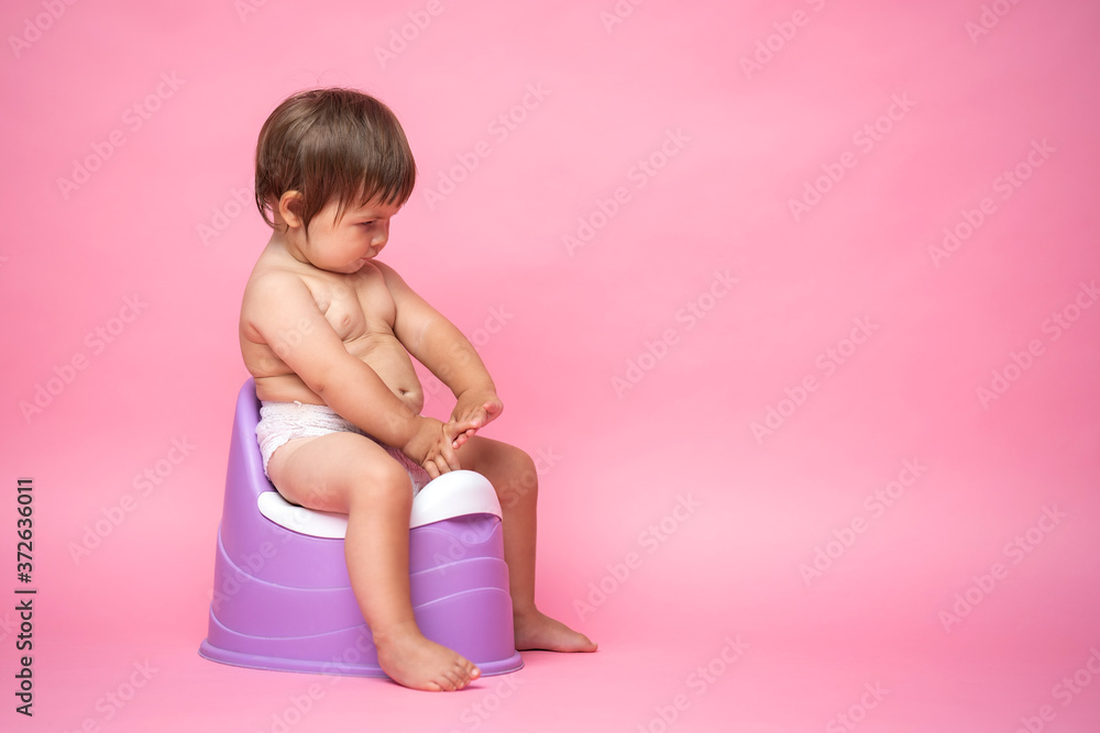 Cute baby in a diaper sitting on a potty. Toilet and potty training. Cute baby in a diaper sitting on a potty. Toilet and potty training.