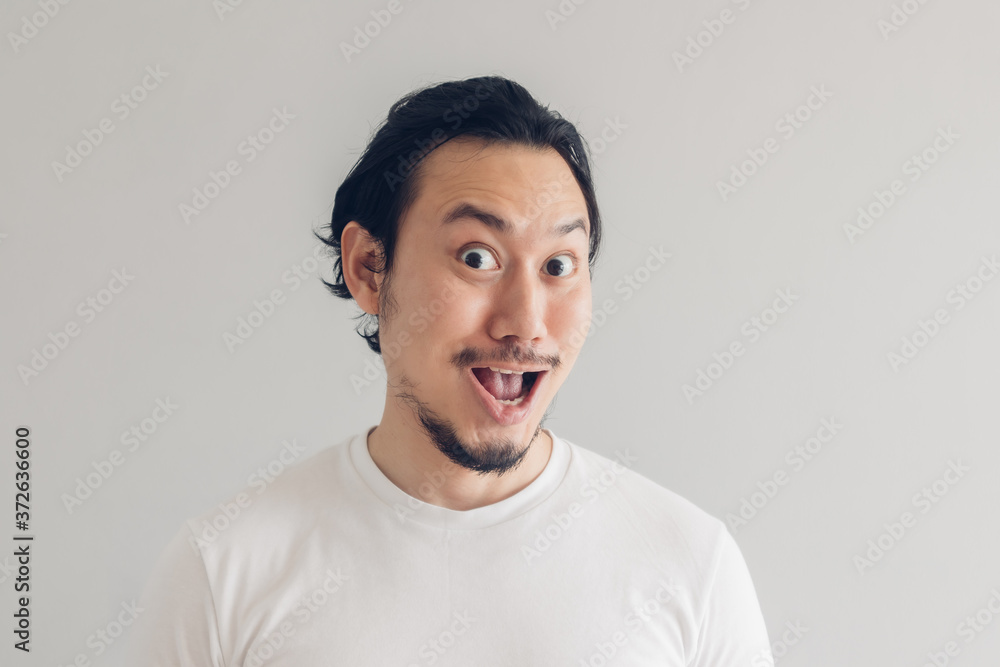 Funny grinning smile face of Asian man in white t-shirt and grey background. Funny grinning smile face of Asian man in white t-shirt and grey background.