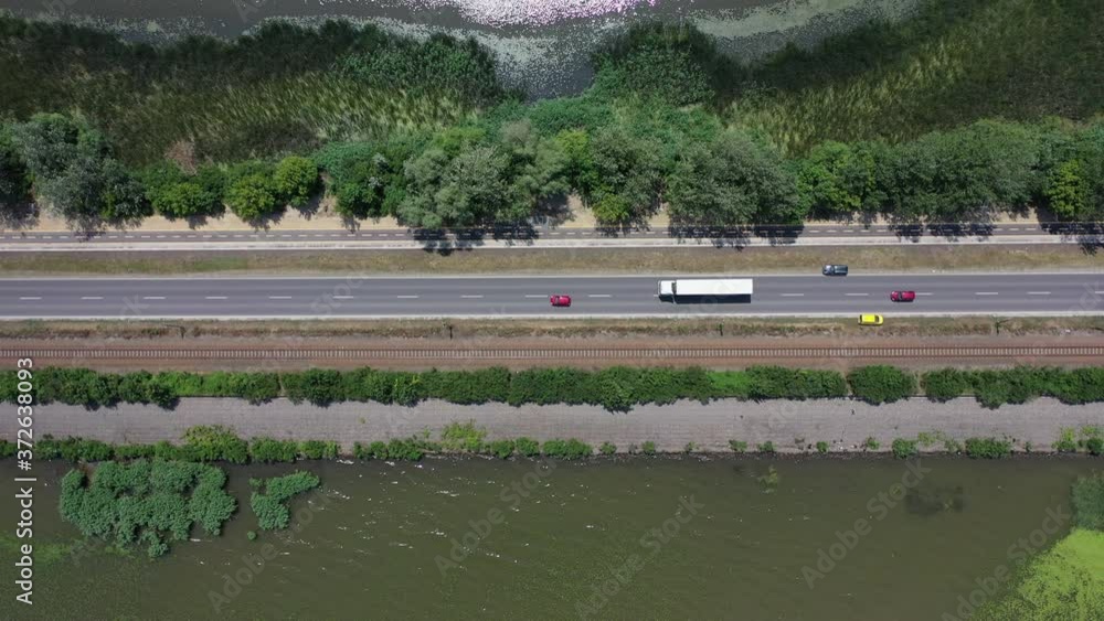 Looking down on a highway with cars and trucks passing by. Steady drone shot. Tisza lake, Hungary Looking down on a highway with cars and trucks passing by. Steady drone shot. Tisza lake, Hungary