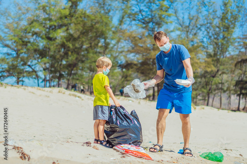 Volunteer blue face mask forest sand beach. Son helps father hold black bag for pick up garbage. Problem spilled rubbish trash planet pollution environmental protection. Natural children education