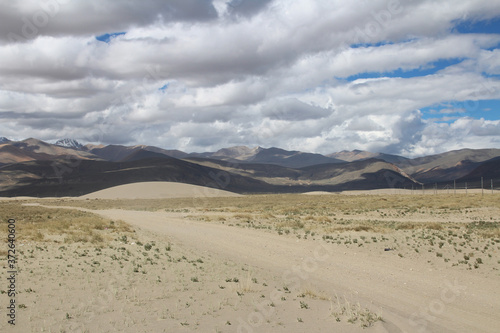 View of the mountain and sand dune with dirt road in a sunny day  Tibet  China