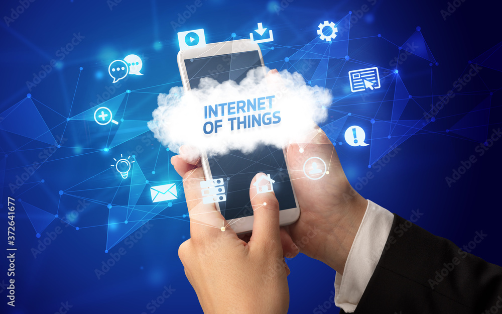 Female hand holding smartphone with INTERNET OF THINGS inscription, cloud technology concept Female hand holding smartphone with INTERNET OF THINGS inscription, cloud technology concept