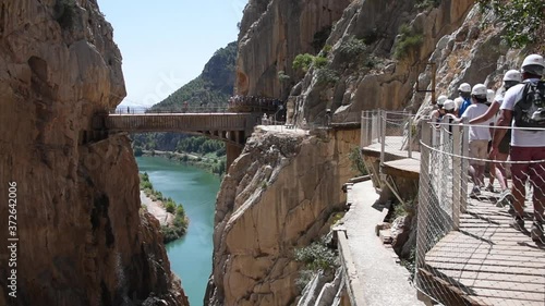 Tourists crossing the Caminito Del Rey suspension bridge over the gorge photo