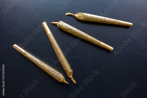 Cannabis Pre-Roll Joints Cigarettes on a leather black texture.