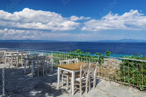 Chalkidiki  Greece empty tavern wooden chairs   table after new covid-19 measures. Restaurant outdoor seating area above the sea without customers in Kallithea  Kassandra peninsula.