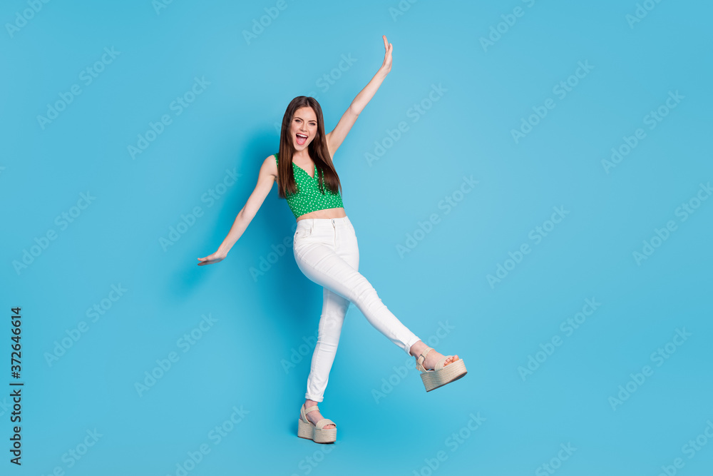 Obraz premium Full size photo of pretty candid crazy girl raise hand leg scream enjoy rejoice summer weekend wear tank-top isolated over blue color background