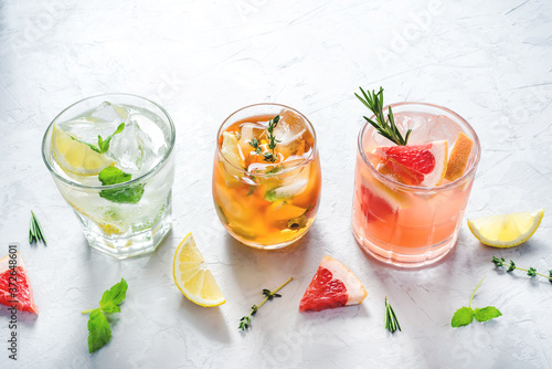 Summer refreshing fruit drinks with ice on a grey background.