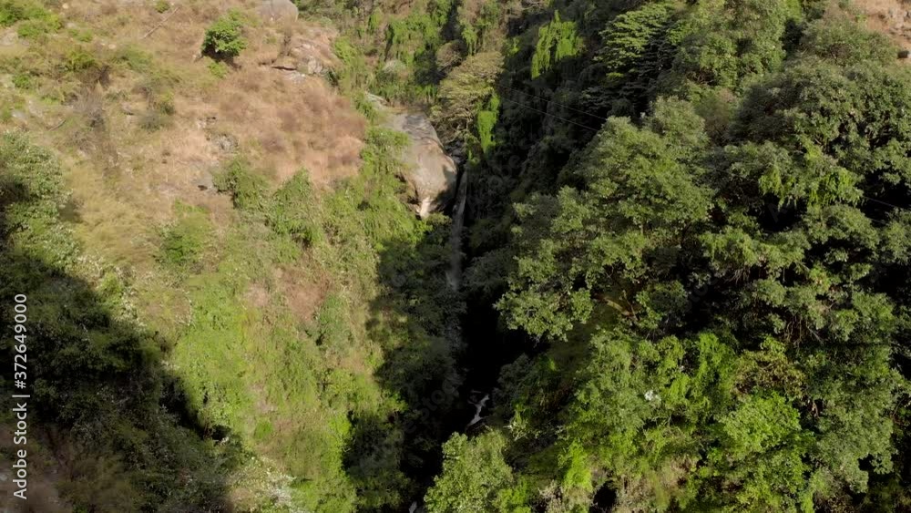 Aerial Dolly Zoom-In shot of a Beautiful huge plunge waterfall covered with trees in Bir, Himachal Pradesh, shot with a drone in 4k. Aerial Dolly Zoom-In shot of a Beautiful huge plunge waterfall covered with trees in Bir, Himachal Pradesh, shot with a drone in 4k.