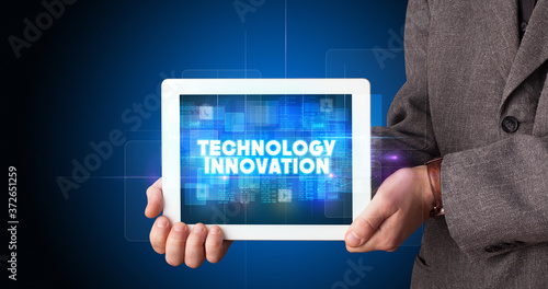 Wallpaper Mural Young business person working on tablet and shows the inscription: TECHNOLOGY INNOVATION Torontodigital.ca