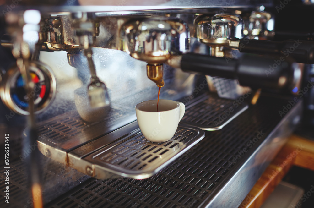 Close-up of espresso pouring from coffee machine.Espresso cup from coffee machine make by barista in shop cafe. Blurred image, selective focus Close-up of espresso pouring from coffee machine.Espresso cup from coffee machine make by barista in shop cafe. Blurred image, selective focus